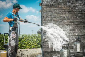Worker power washing brick wall